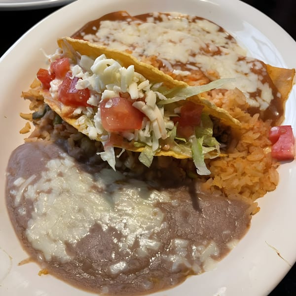 A Fiesta Grande Mexican Grill plate with a taco, rice, refried beans, and enchiladas.