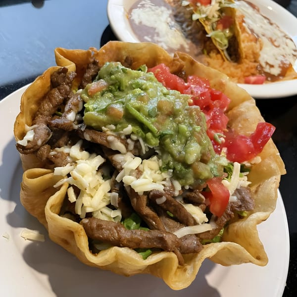 A Fiesta Grande Mexican Grill taco salad in a crispy shell, topped with steak, guacamole, and tomatoes.