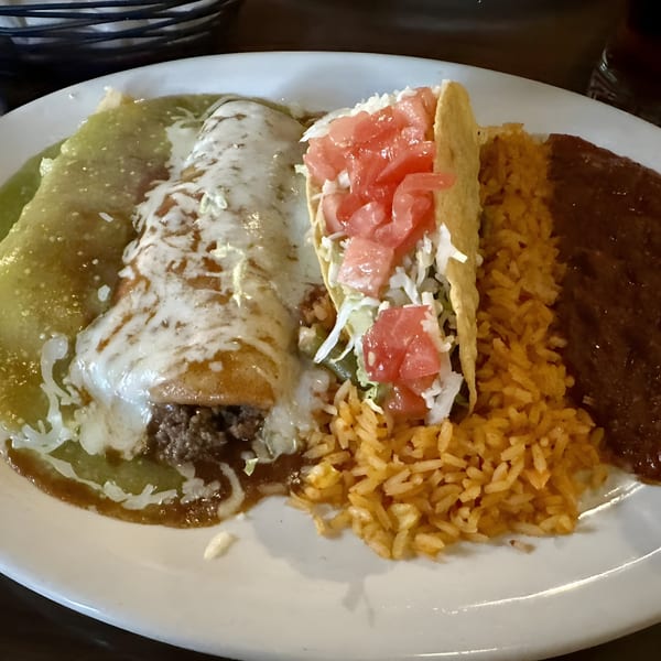 A Fiesta Grande Mexican Grill plate with a green enchilada, a taco, rice, and refried beans.